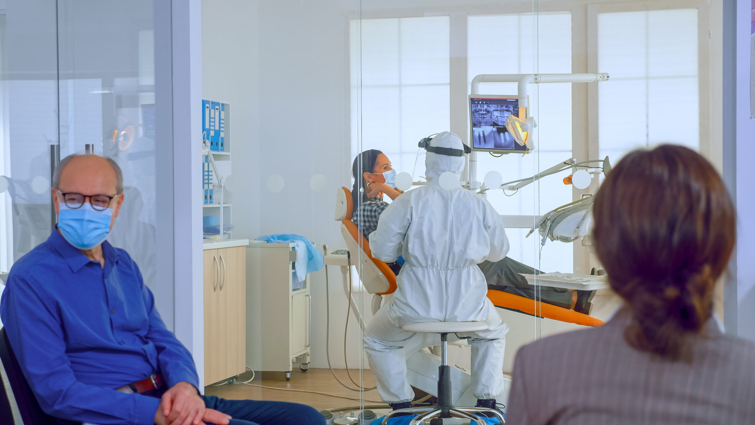 people-with-protection-masks-discussing-reception-area-waiting-doctor-dental-clinic-while-stomatologist-working-background-wearing-ppe-suit-concept-new-normal-dentist-visit