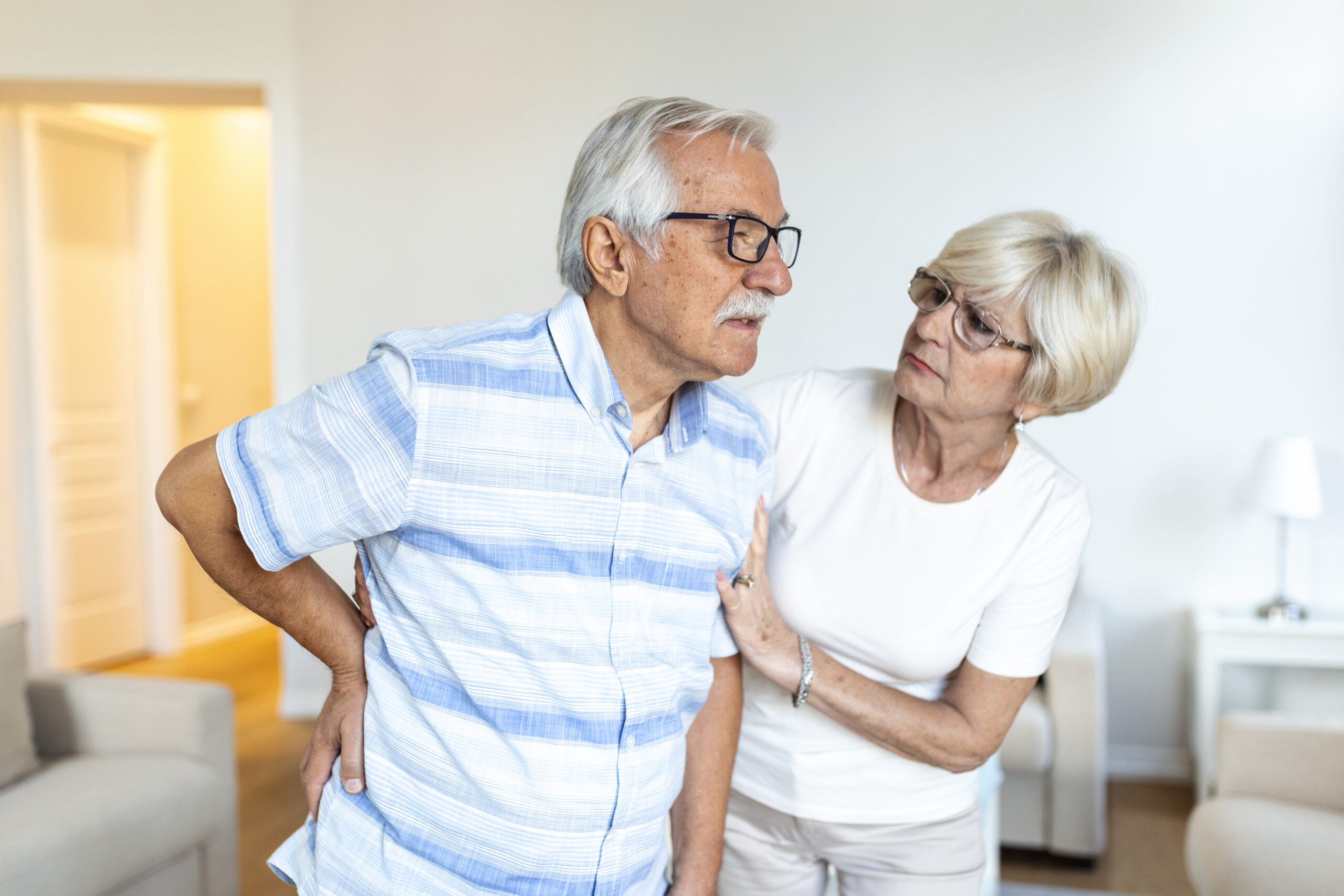 Senior couple at home.Elderly man is having back pain and his lovley wife supports him.